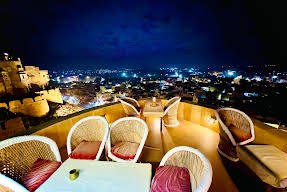 Rooftop wicker seating at night with city lights